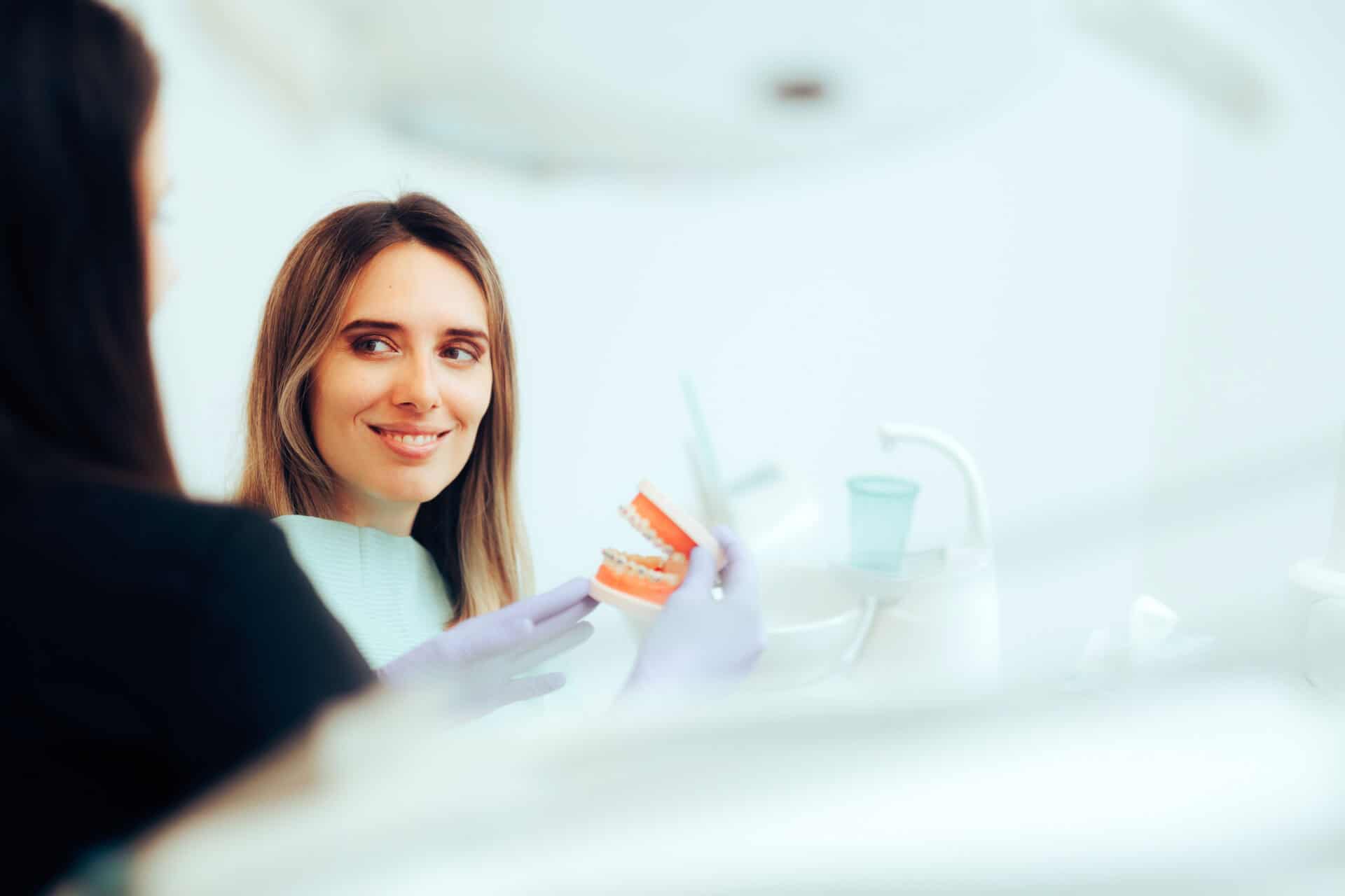 Orthodontist Showing His Patient a Tooth Model and Treatment Plan. Dentist presenting his strategy to his client ready for orthodontic braces